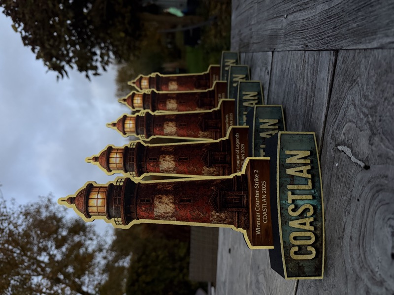 Printed lighthouse trophies for CoastLAN 2025 lined up on a wooden table